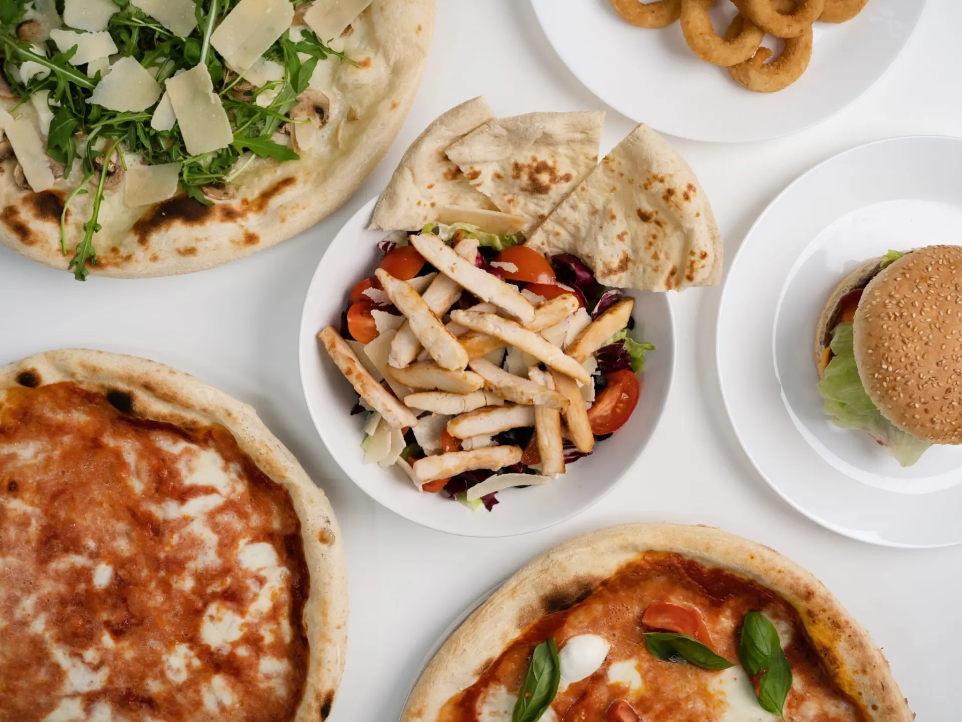 Pizze, piadine, insalata, hamburger e fritti su sfondo bianco